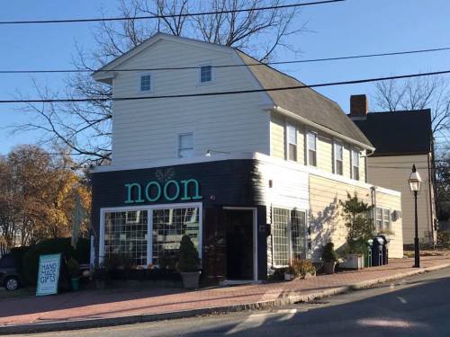 A two-story building with a sign reading "noon," featuring large windows and a cozy entrance.