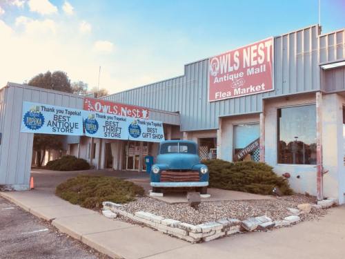Exterior of Owls Nest Antique Mall and Flea Market, featuring a vintage truck and colorful banners promoting the store.