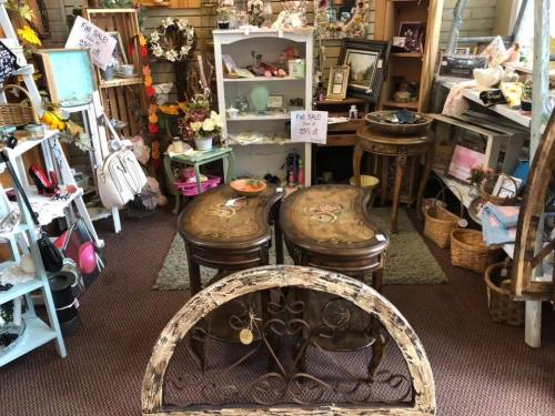 A cozy vintage shop filled with furniture, decor, and knick-knacks, featuring a fall sale sign and various items for sale.