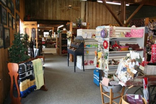 A cozy shop interior featuring wooden walls, shelves of crafts, and various handmade items for sale.