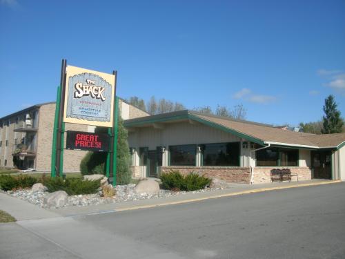 A restaurant called "The Shack" with a sign advertising great prices, surrounded by landscaping and a clear blue sky.