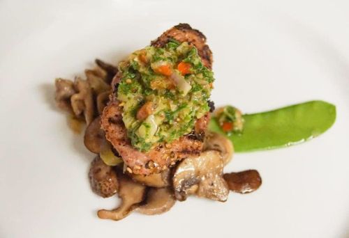 Grilled salmon topped with a vibrant herb salsa, served on sautéed mushrooms and a sugar snap pea.