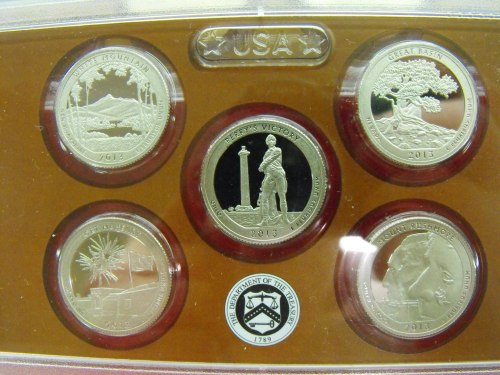 A display of five commemorative coins featuring various U.S. national parks and historical themes, encased in a protective holder.