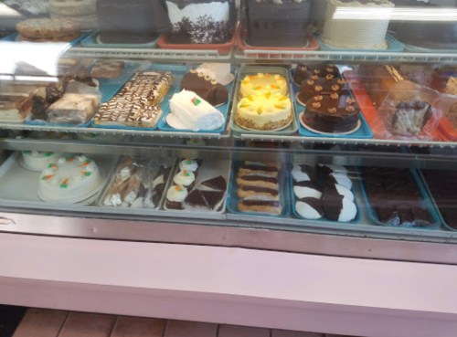 A display case filled with various cakes and pastries, including chocolate, cream, and decorated desserts.