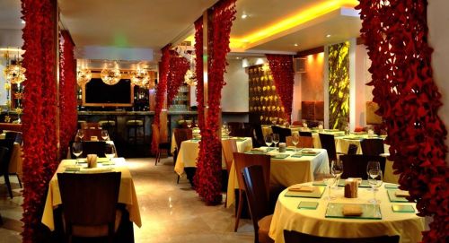 Elegant restaurant interior with red floral decor, soft lighting, and neatly set tables.