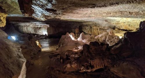 A dimly lit cave interior with rocky formations and a reflective water surface.