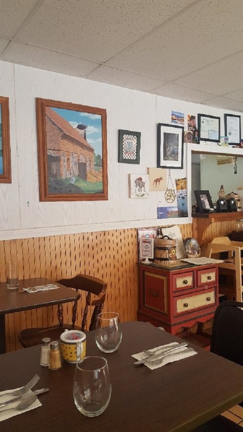 Cozy restaurant interior with wooden furniture, wall art, and decorative items, creating a warm atmosphere.