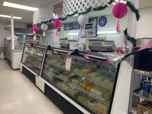 A decorated deli display case filled with various cheeses and meats, featuring festive decorations and lights.