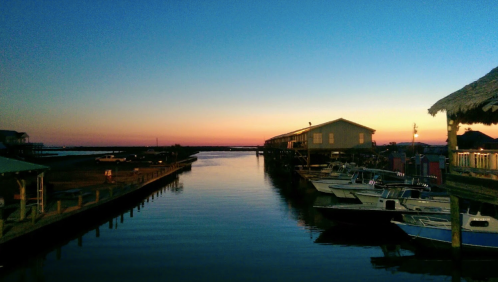 Sunset over a calm marina, with boats docked and colorful sky reflecting on the water.