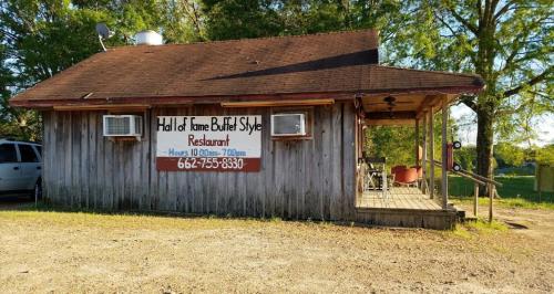 A rustic restaurant with a wooden exterior and a sign reading "Hall of Fame Buffet Style Restaurant" in a rural setting.
