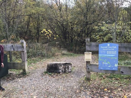 Entrance to Emerald View Park, featuring a sign and a stone marker, surrounded by trees and autumn foliage.