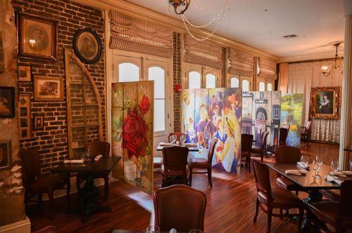 Cozy restaurant interior with wooden floors, elegant tables, and colorful art panels creating a warm atmosphere.