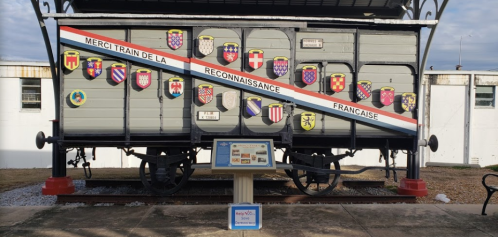 A historic train car displaying various coats of arms and a sign thanking for French recognition.