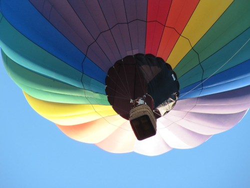 A colorful hot air balloon viewed from below, with a clear blue sky in the background.