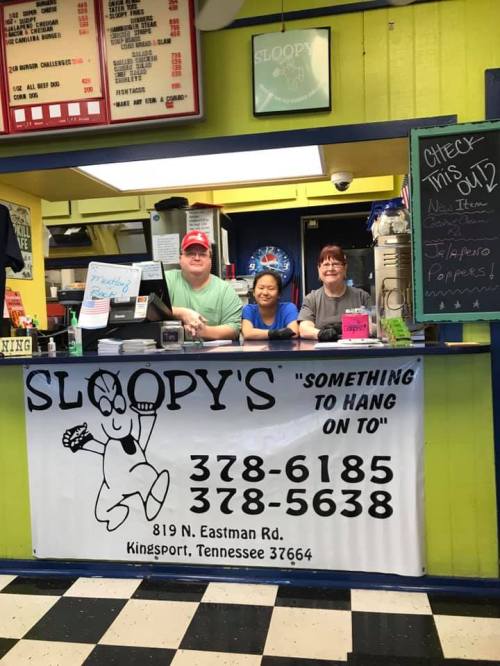 A colorful restaurant counter with three staff members smiling behind a sign for Sloopy's in Kingsport, Tennessee.