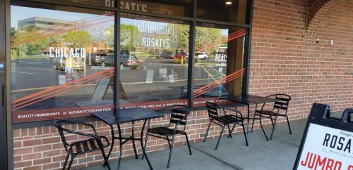 Exterior view of a pizza restaurant with outdoor seating and a sign that says "Open" and "Chicago Pizza."