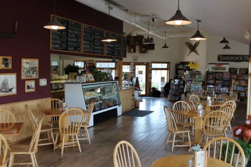 Cozy café interior with wooden tables, a display case, and a menu board, featuring a welcoming atmosphere.