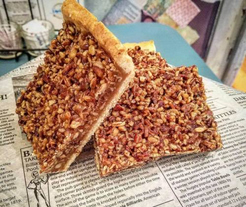Two slices of pecan pie on a piece of newspaper, showcasing a golden crust and a rich, nutty filling.