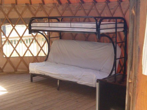 A cozy yurt interior featuring a bunk bed and a futon on a wooden floor.