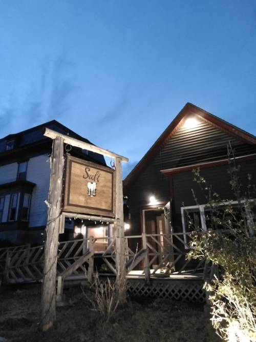 A cozy building with a sign reading "Salt" illuminated at dusk, surrounded by greenery and a clear blue sky.