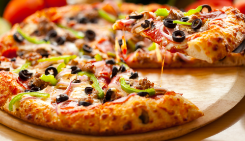 A close-up of a delicious pizza topped with olives, green peppers, onions, and sausage, with a slice being lifted.