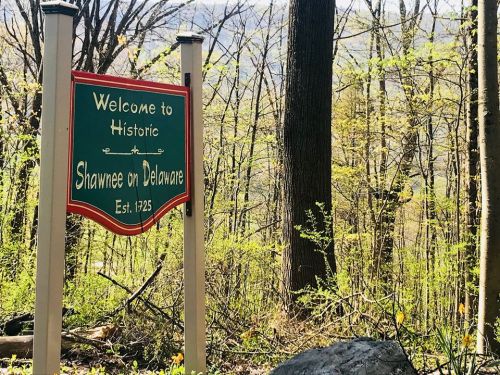 Welcome sign for Historic Shawnee on Delaware, established 1725, surrounded by trees and greenery.