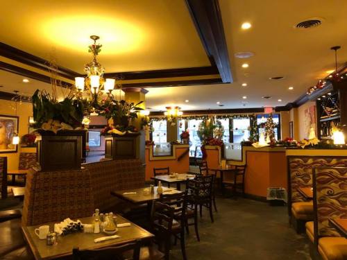 Cozy restaurant interior decorated for the holidays, featuring tables, chairs, and festive floral arrangements.