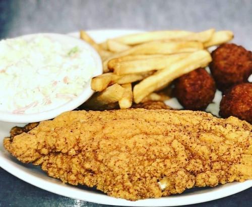 A plate of fried fish, French fries, hushpuppies, and coleslaw.