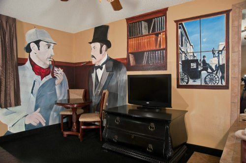 A room featuring murals of Sherlock Holmes and Dr. Watson, with a TV and a small table in front.