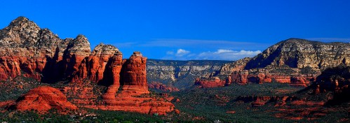 Vibrant red rock formations and cliffs under a clear blue sky in a scenic desert landscape.