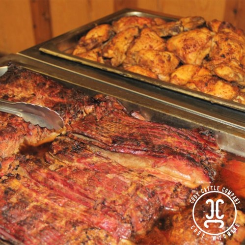 A close-up of grilled meat and a tray of seasoned chicken, showcasing a delicious barbecue spread.