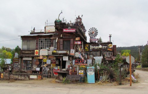 A quirky, multi-level building adorned with various vintage signs and decorations, set in a rural landscape.