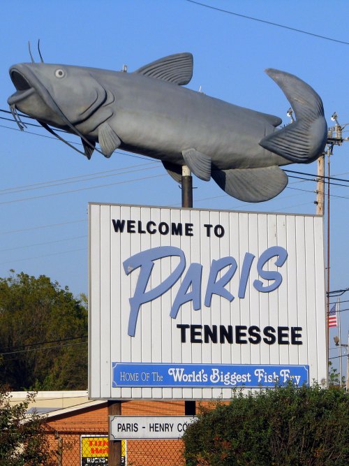 Welcome sign for Paris, Tennessee, featuring a large fish sculpture and text about the world's biggest fish fry.