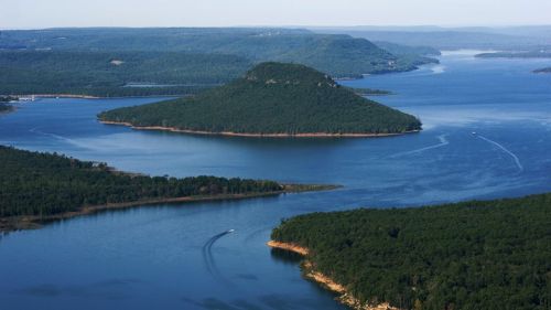 Aerial view of a serene lake with a small island and lush green forests surrounding the water.