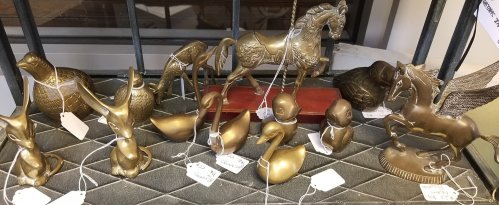 A collection of bronze animal figurines, including a horse, birds, and a winged horse, displayed on a shelf.