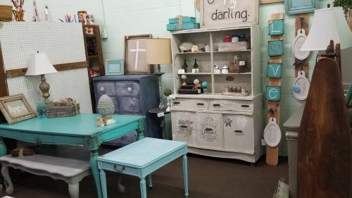 A cozy room filled with vintage furniture, including a turquoise table, lamps, and decorative shelves.