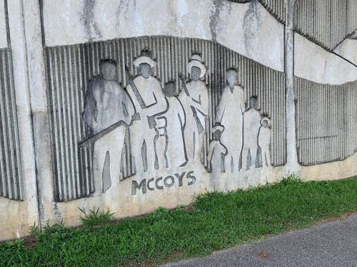 A textured mural depicting figures in various poses, with the word "MCCOYS" prominently displayed at the bottom.