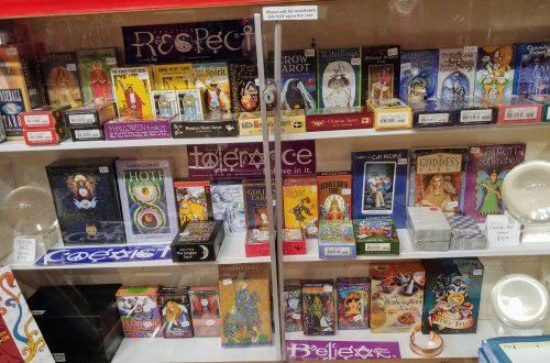 A display case filled with various tarot card decks and related items, showcasing colorful packaging and designs.