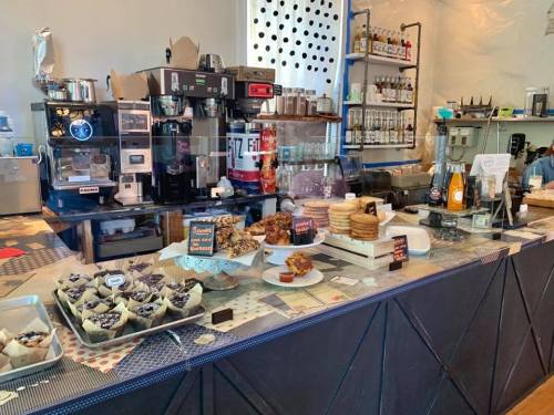 A cozy café display featuring various baked goods, coffee machines, and drinks on a counter.