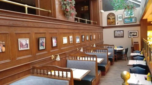 Interior of a restaurant featuring wooden paneling, booths, and framed photos on the walls.
