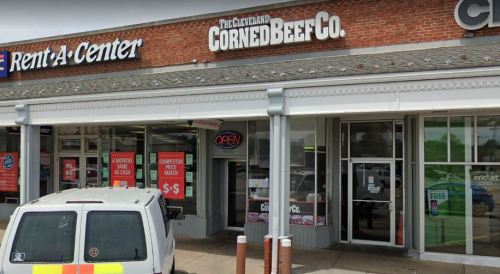 Exterior view of a storefront featuring "The Cleveland Corned Beef Co." sign, with an open sign and a parked vehicle.