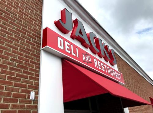 Sign for "Jacky's Deli and Restaurant" on a brick building with a red awning.