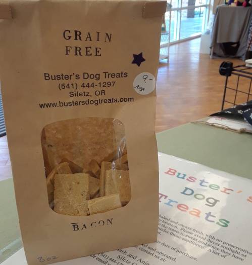 A bag of Buster's Dog Treats labeled "Grain Free Bacon," with a clear window showing the treats inside.