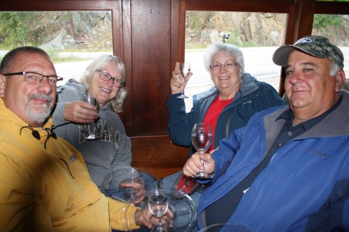 Four people sitting together in a cozy setting, each holding a glass, smiling and enjoying their time.