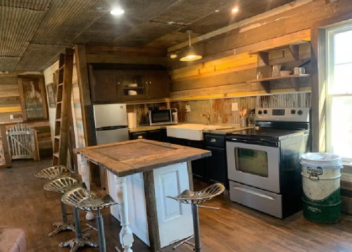 Cozy kitchen with rustic wood walls, stainless steel appliances, and a central island with bar stools.