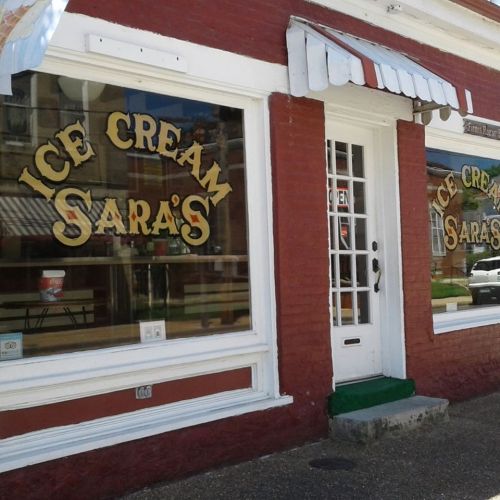 Exterior of Sara's Ice Cream shop with large windows and a striped awning, showcasing the shop's name.