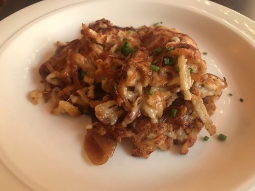 A plate of crispy, golden-brown potato pancakes topped with chopped chives.