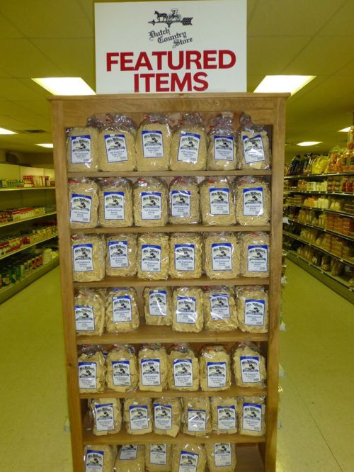 A wooden display shelf filled with bags of featured items at a store, labeled "Featured Items" above.