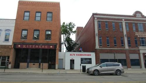 A street view featuring Kittner's store and Al's Hamburger, with a parked car in front of the buildings.