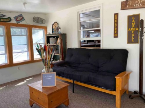 Cozy interior with a black futon, wooden coffee table, and decorative signs in a well-lit room.
